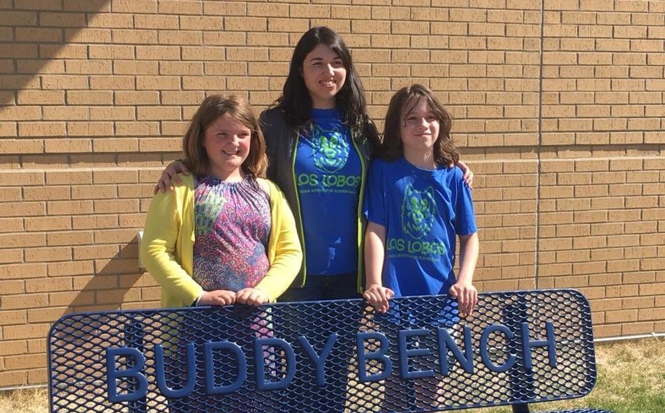 Student Emily(left) and Teacher Noah (middle) standing behind a Buddy Bench Student Emily(left) and Teacher Noah (middle) standing behind a Buddy Bench